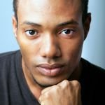 Close-up portrait of a young African American man posing in a studio setting.